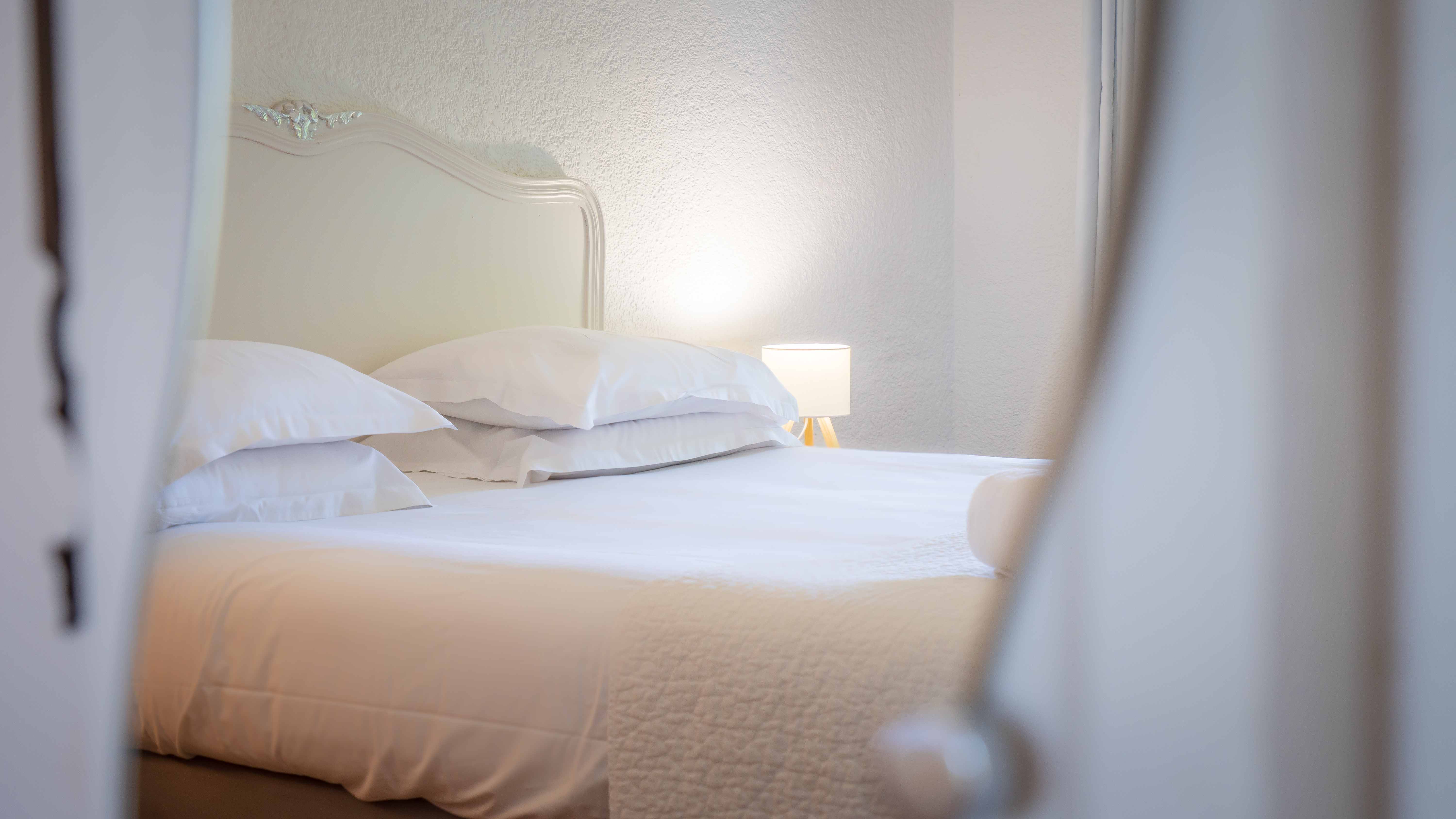 Lit tout blanc avec lampes de chevet allumées, chambre lumineuse et épurée